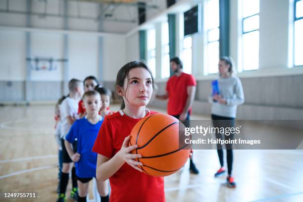 group of pupils with teacher exercising indoors in gym class, playing basketball. - sportunterricht stock-fotos und bilder