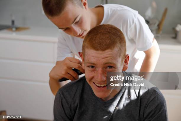 a young man smiles whilst having a home hair cut by another teenage boy. - cut out happy ストックフォトと画像