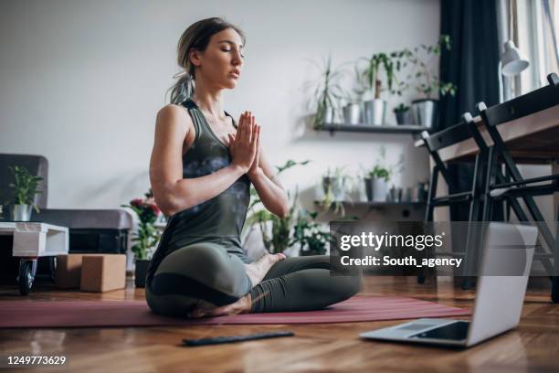 beautiful woman meditating with online guru - online yoga stock pictures, royalty-free photos & images