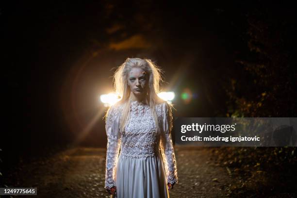 zombie in wedding dress standing on a road at night - halloween zombie makeup imagens e fotografias de stock