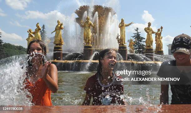 Youngsters enjoy cold water in the Soviet era "Fountain of the Nations' Friendship", at All-Russian Exhibition Center in Moscow on July 7, 2010. The...