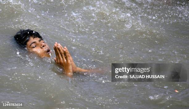 An Indian child prays as he swims in the waters of The Arabian Sea in Mumbai, 15 July 2007, as high tide approaches the western Indian city. The...