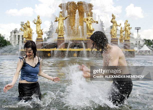 Two teenagers cool themselves, as temperatures soared over 30 degrees Celsius, in a fountain representative of the friendship of nations of the...