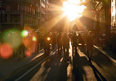 Crowd of people walking down the street into the bright light of sunset in New York City