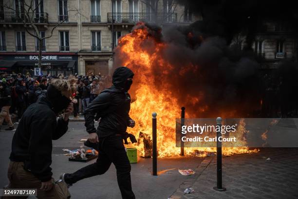 Protesters run past a fire during a rally against pension reforms on March 28, 2023 in Paris, France. The country has experienced weeks of protests...