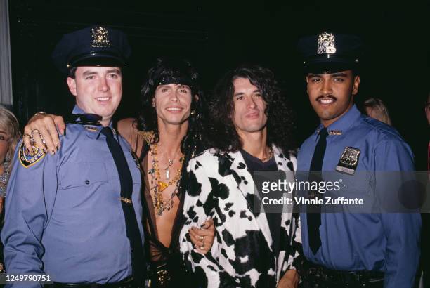 American singer Steven Tyler and American guitarist Joe Perry, both of rock band Aerosmith, posing between two NYPD officers at the 2nd International...