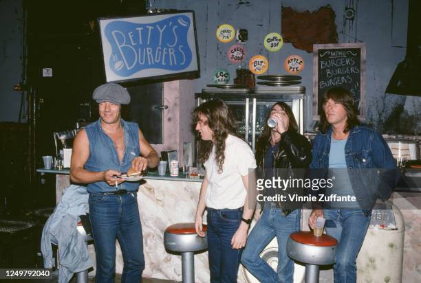 Australian rock band AC/DC sitting at the counter of a branch of Betty's Burgers, circa 1990.