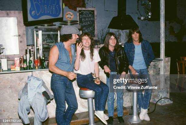 Australian rock band AC/DC sitting at the counter of a branch of Betty's Burgers, circa 1990.