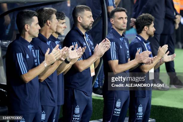 Argentina's coach Lionel Scaloni applauds next to Argentina's goalkeeper coach Martin Tocalli, physical trainer Jose Martin, and assistant coaches...