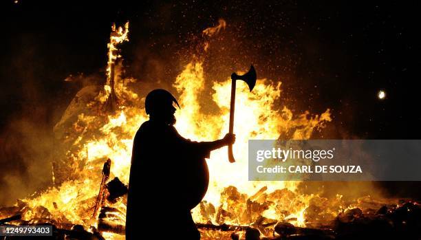 Member of the Jarl viking squad is silhoutted by a burning viking longship during the annual Up Helly Aa Festival, Lerwick, Shetland Islands, January...
