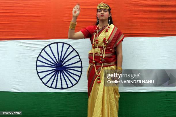 School girl dressed as Bharat Mata, known as Mother India, stands in the front of the Indian national flag during celebrations for India's 60th...