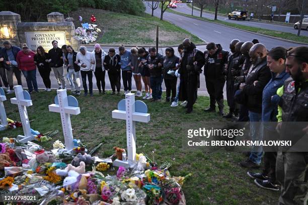 Members of the Selected First Motorcycle Club join others in prayer at a makeshift memorial for victims of a shooting at the Covenant School campus,...