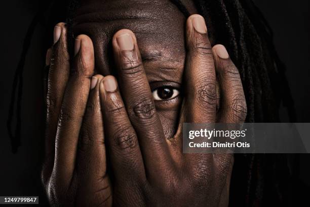 man covering his face peeking through gap between two fingers - racism stock pictures, royalty-free photos & images