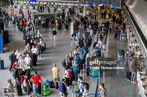 Tourists wait to check in for a TUIfly flight to Mallorca at Frankfurt Airport on the first day that package tours are resuming since March during...