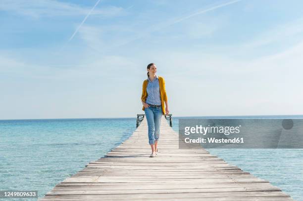 happy woman walking on jetty, mallorca, spain - pier stock-fotos und bilder