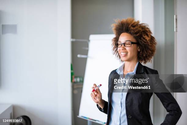 smiling businesswoman leading a presentation at flip chart in office - flipchart stock-fotos und bilder