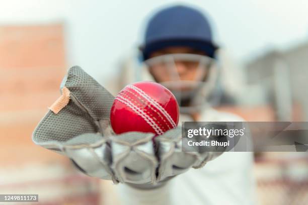 a boy in cricket uniform and wearing keeper gloves with hold leather ball. and doing practice - luva roupa desportiva de proteção imagens e fotografias de stock