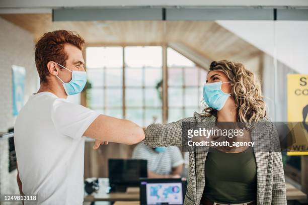 colleagues greeting each other with elbows in office during covid-19 pandemic - covid greeting stock pictures, royalty-free photos & images