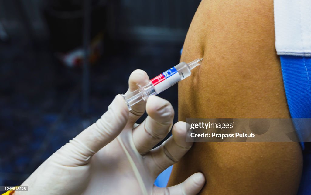 Doctor giving patient vaccine, flu or influenza shot or taking blood test with needle. Nurse with injection or syringe. Medicine, insulin or vaccination. Hospital office room.