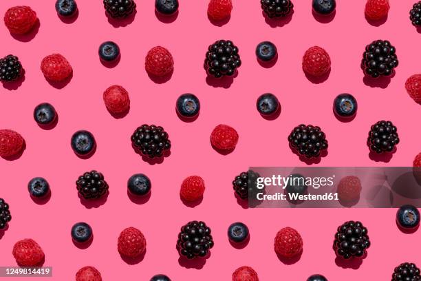 pattern of raspberries, blueberries and blackberries against pink background - raspberry imagens e fotografias de stock