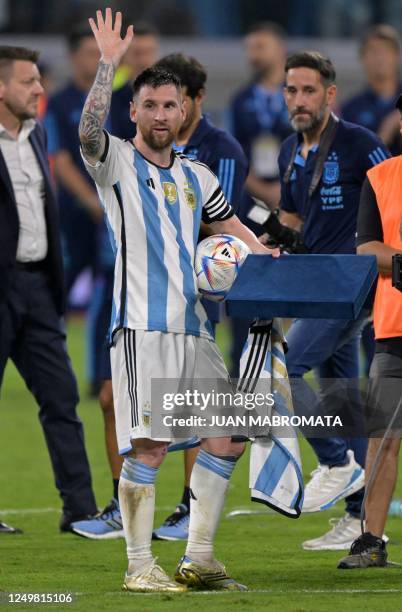 Argentina's forward Lionel Messi waves at the crowd after receiving the match ball for scoring a hat-trick and a jersey for his 100th goal with the...