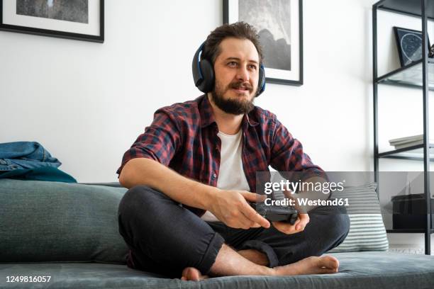 man sitting on couch and playing video game - game one stockfoto's en -beelden