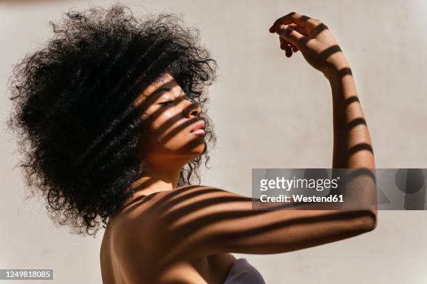 portrait of young woman with shadow on her body - afro hairstyle stock-fotos und bilder
