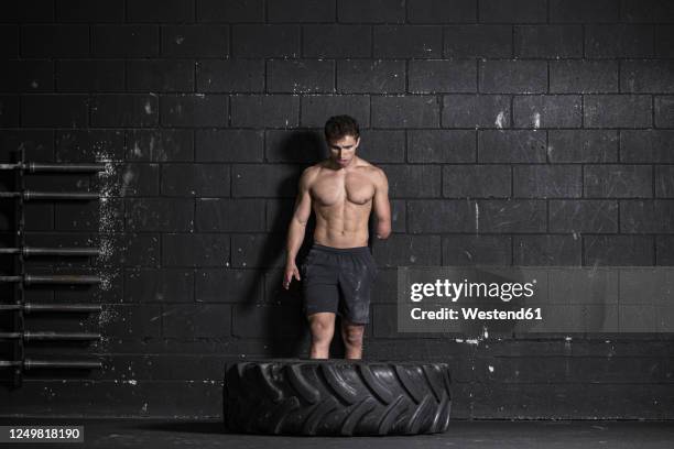 athlete with an amputated arm exercising with tractor tire - amputee stock-fotos und bilder