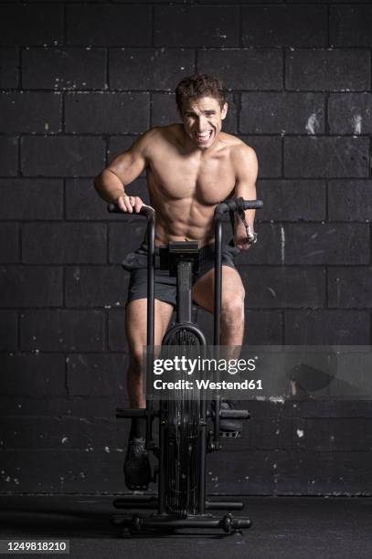 athlete with an amputated arm doing air bike workout - cyclette foto e immagini stock