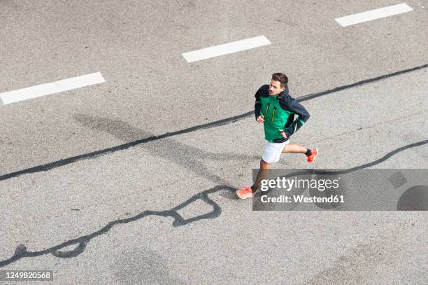 bird's eye view of young man running on a road - laufwettbewerb der männer stock-fotos und bilder