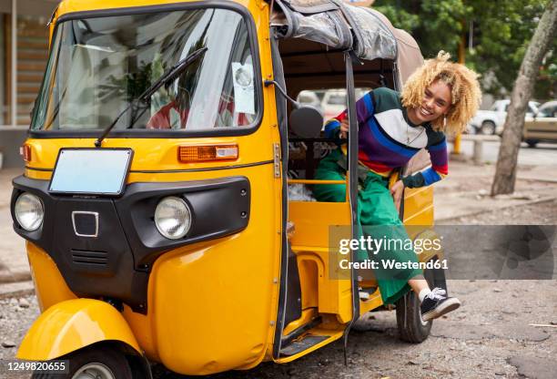 full length portrait of smiling young woman leaning out from tuk-tuk in city - taxi españa stockfoto's en -beelden