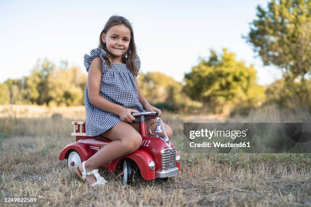 portrait of smiling little girl with pedal car in nature - bobbycar stock pictures, royalty-free photos & images