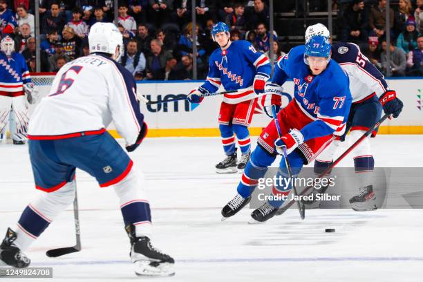 Niko Mikkola of the New York Rangers skates with the puck against Billy Sweezey of the Columbus Blue Jackets at Madison Square Garden on March 28,...