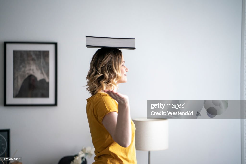 Woman at home balancing a book on her head