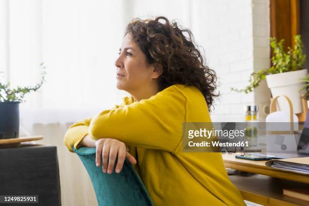 brunette woman having a break in home office - brunette sitting at desk stock-fotos und bilder