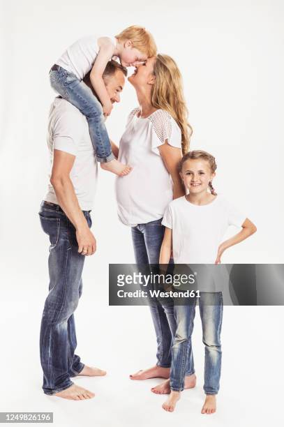 pregnant woman with husband and two children standing in front of white background - jeans barefoot girl stock pictures, royalty-free photos & images