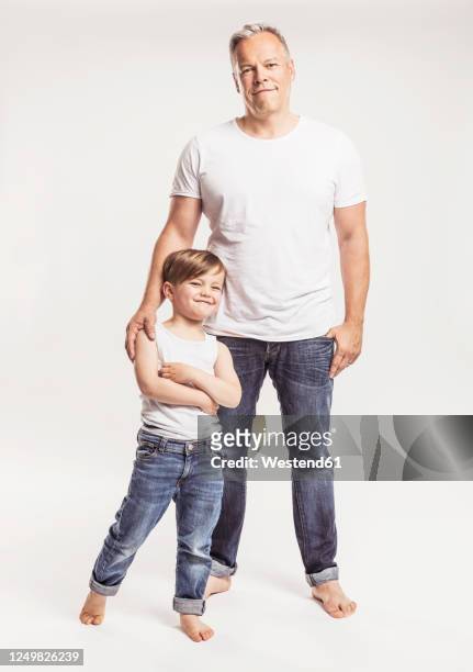 portrait of father and his little son standing in front of white background - kids standing crossed arms stock pictures, royalty-free photos & images