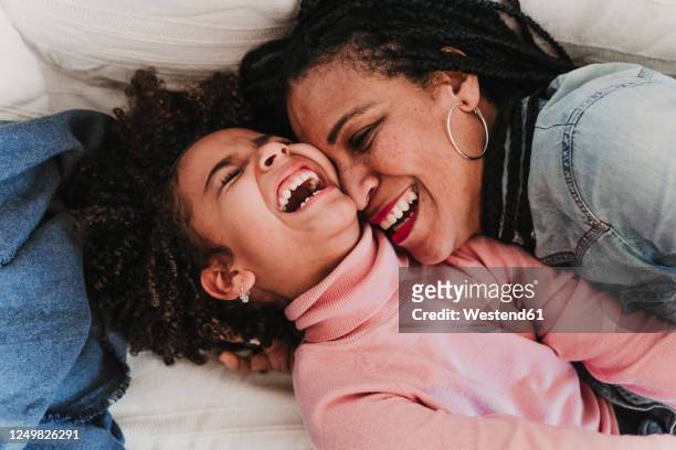 portrait of laughing little girl and her mother having fun together at home - afro jokes stock-fotos und bilder