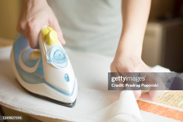 closeup image of woman hand ironing baby diapers - inzoomen stockfoto's en -beelden