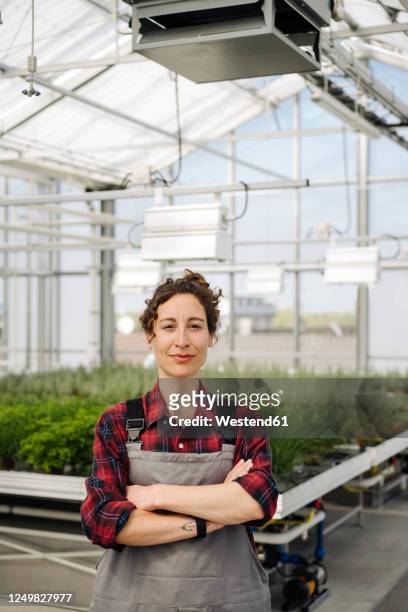 portrait of confident woman in greenhouse of a gardening shop - plaid shirt stock-fotos und bilder