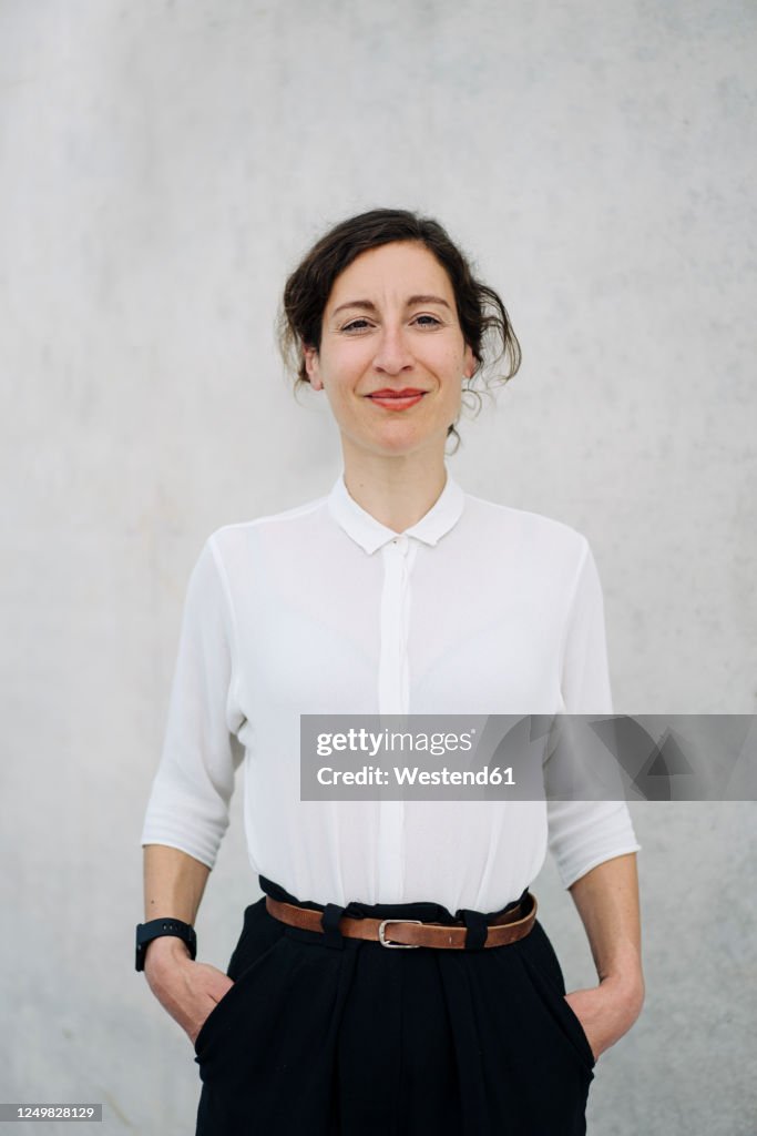 Portrait of a smiling businesswoman at a concrete wall