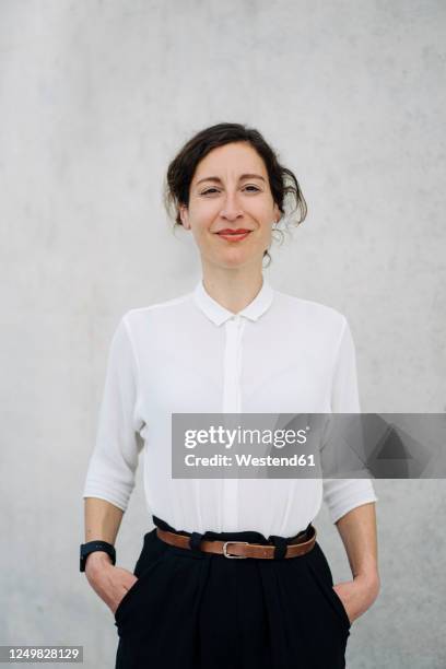 portrait of a smiling businesswoman at a concrete wall - white blouse stock pictures, royalty-free photos & images