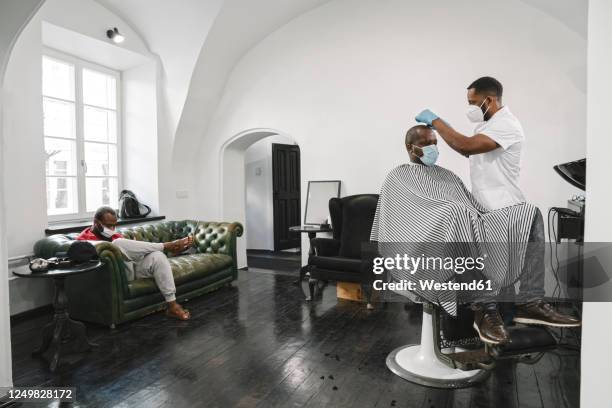 barber wearing surgical mask and reusable gloves cutting hair of the customer - barber shop 3 stock pictures, royalty-free photos & images