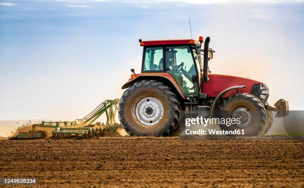 farmer in tractor plowing field in spring - tractor foto e immagini stock