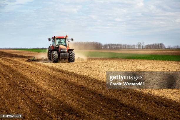 farmer in tractor plowing field in spring - tractor foto e immagini stock