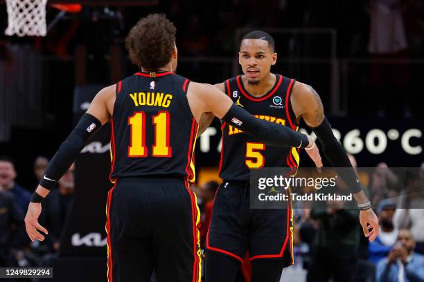 Dejounte Murray reacts with Trae Young of the Atlanta Hawks during the second half against the Cleveland Cavaliers at State Farm Arena on March 28,...