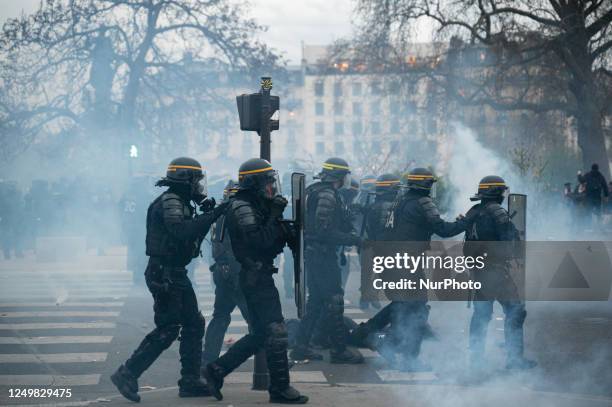 Riot police officers are walking amidst a protester on the ground in tear gas as several thousand protesters march in a demonstration in Paris,...
