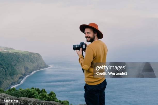 smiling man with a camera at the coast on sao miguel island, azores, portugal - photographer 個照片及圖片檔