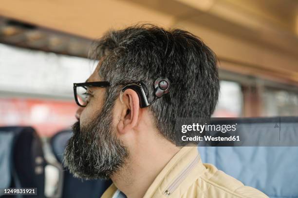 profile of a man with cochlear implant in a train - hearing aids stock pictures, royalty-free photos & images