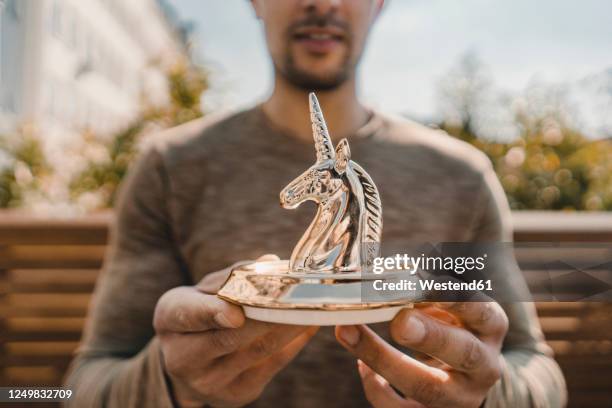 young entrepreneur holding unicorn figurine, close up - 庭の置物 ストックフォトと画像